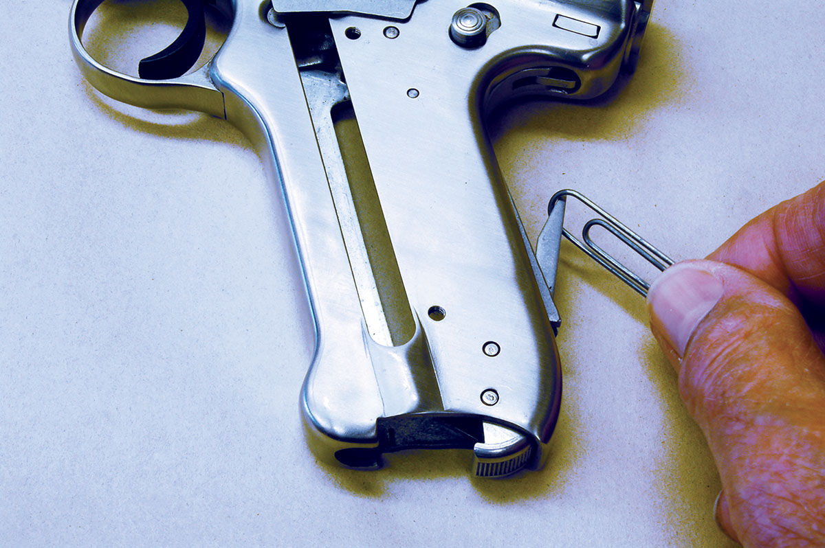 To begin disassembly, remove the magazine, grips and make certain the gun is not cocked. Then pull out the bolt stop assembly lever using a large paper clip.